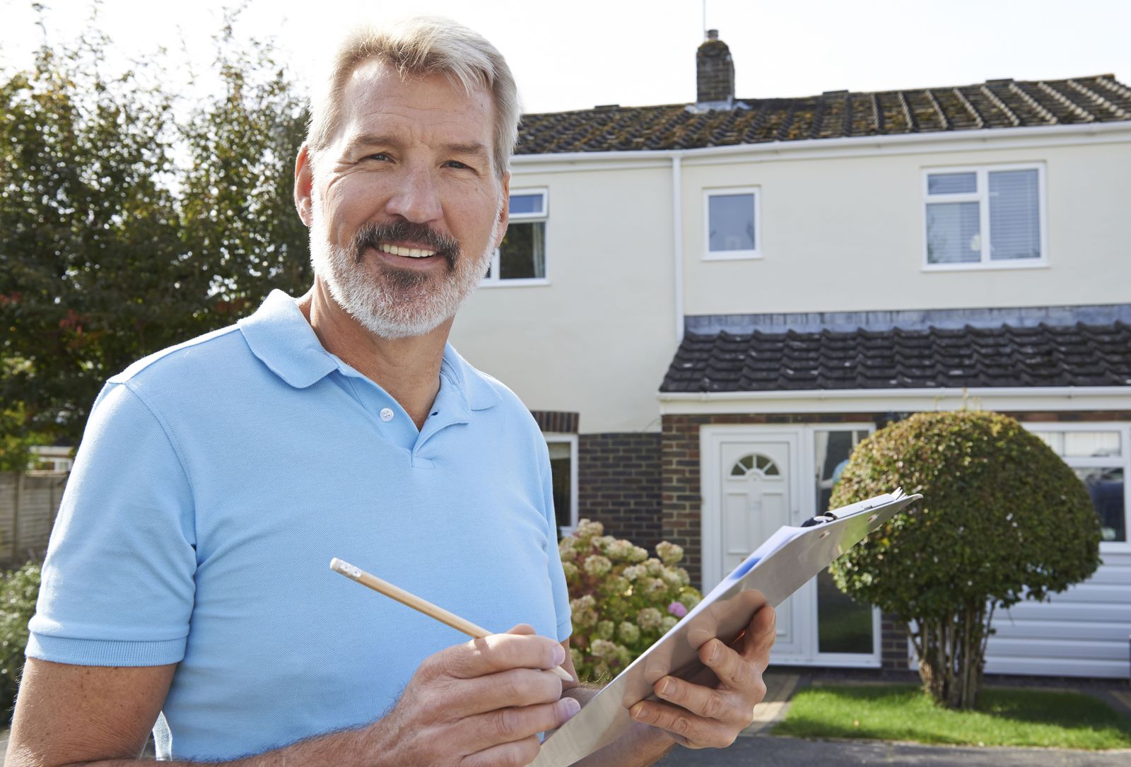 Tomas, owner of Harbor Point Roofing, with a clipboard in front of a house