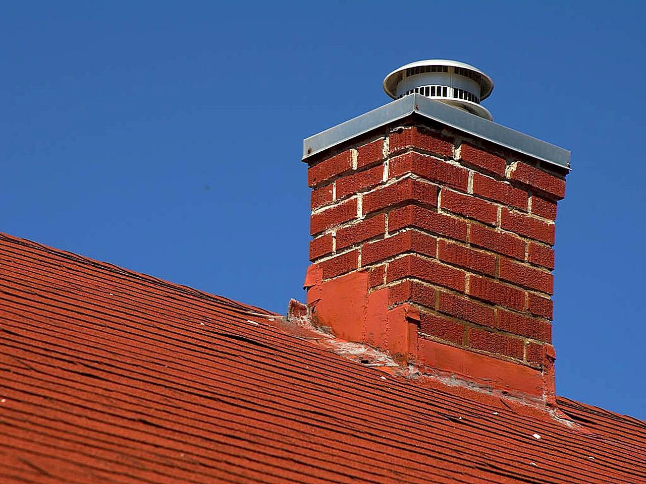 Brick chimney on a red tile roof with new flashing at the base